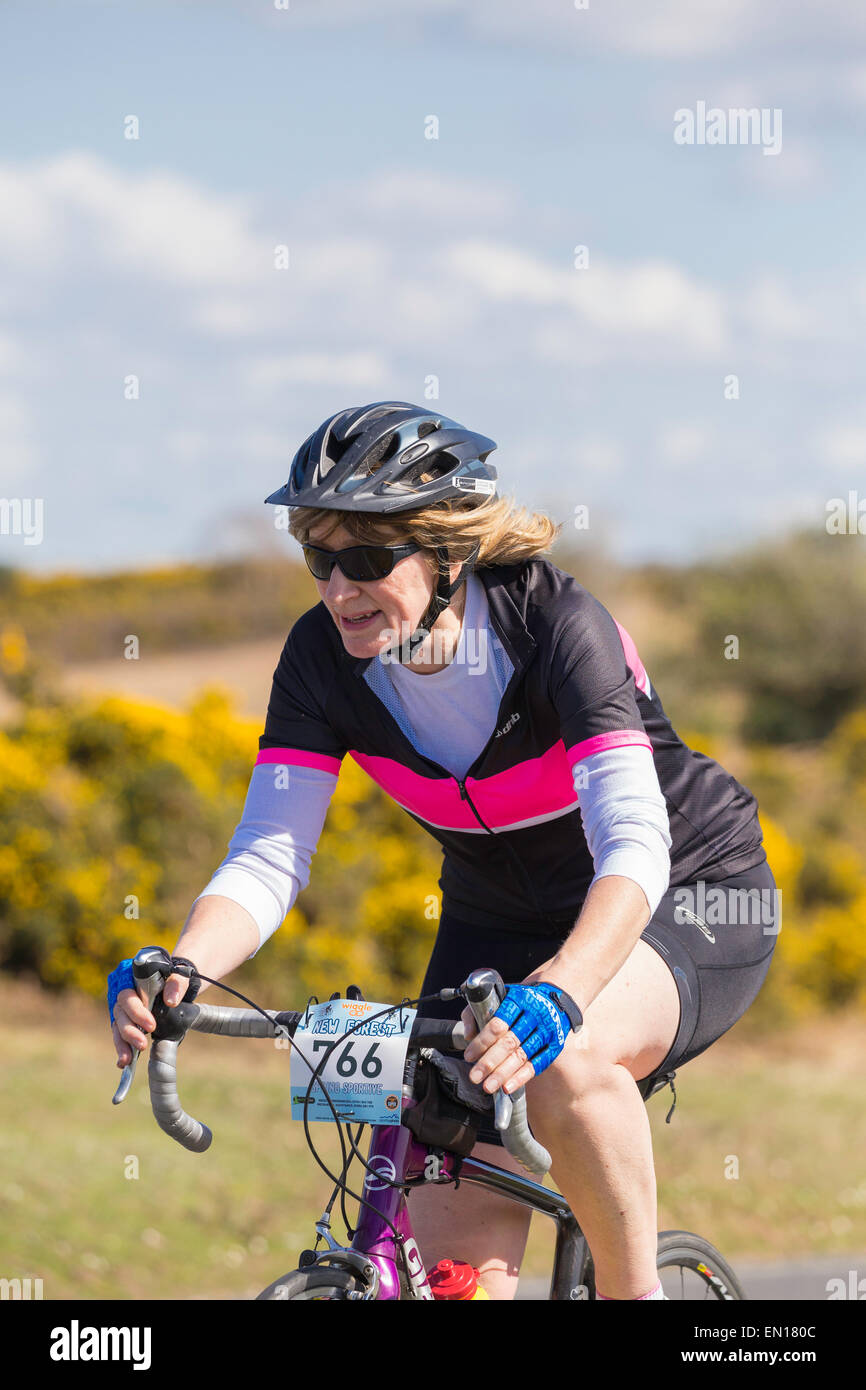 A middle-aged female cyclist competes in the New Forest Wiggle Sportive event on a sunny Sunday in Spring Stock Photo