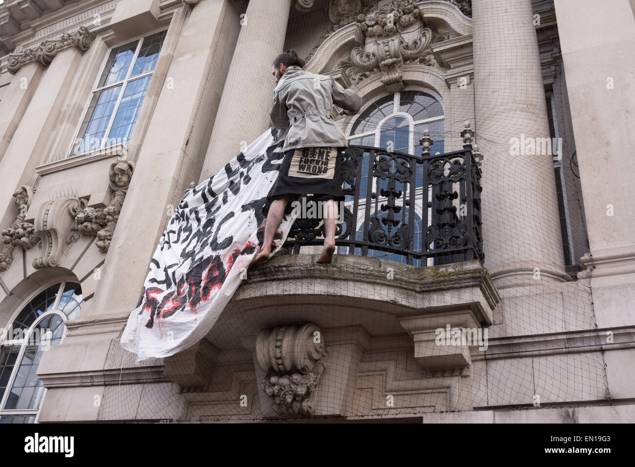 Brixton, London, 25th April 2015 A barefoot protester attatches a banner to an ornate balcony on the Town Hall as anti-gentrification protesters march through Brixton in London. Credit:  Patricia Phillips/Alamy Live News Stock Photo