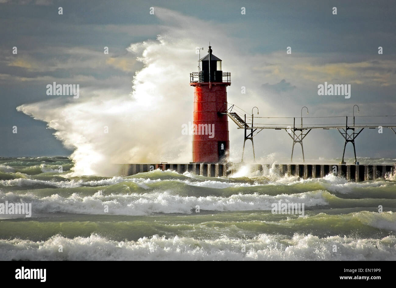 Wild wave crashing on a red lighthouse at the end of a pier in South Haven, Michigan. Stock Photo