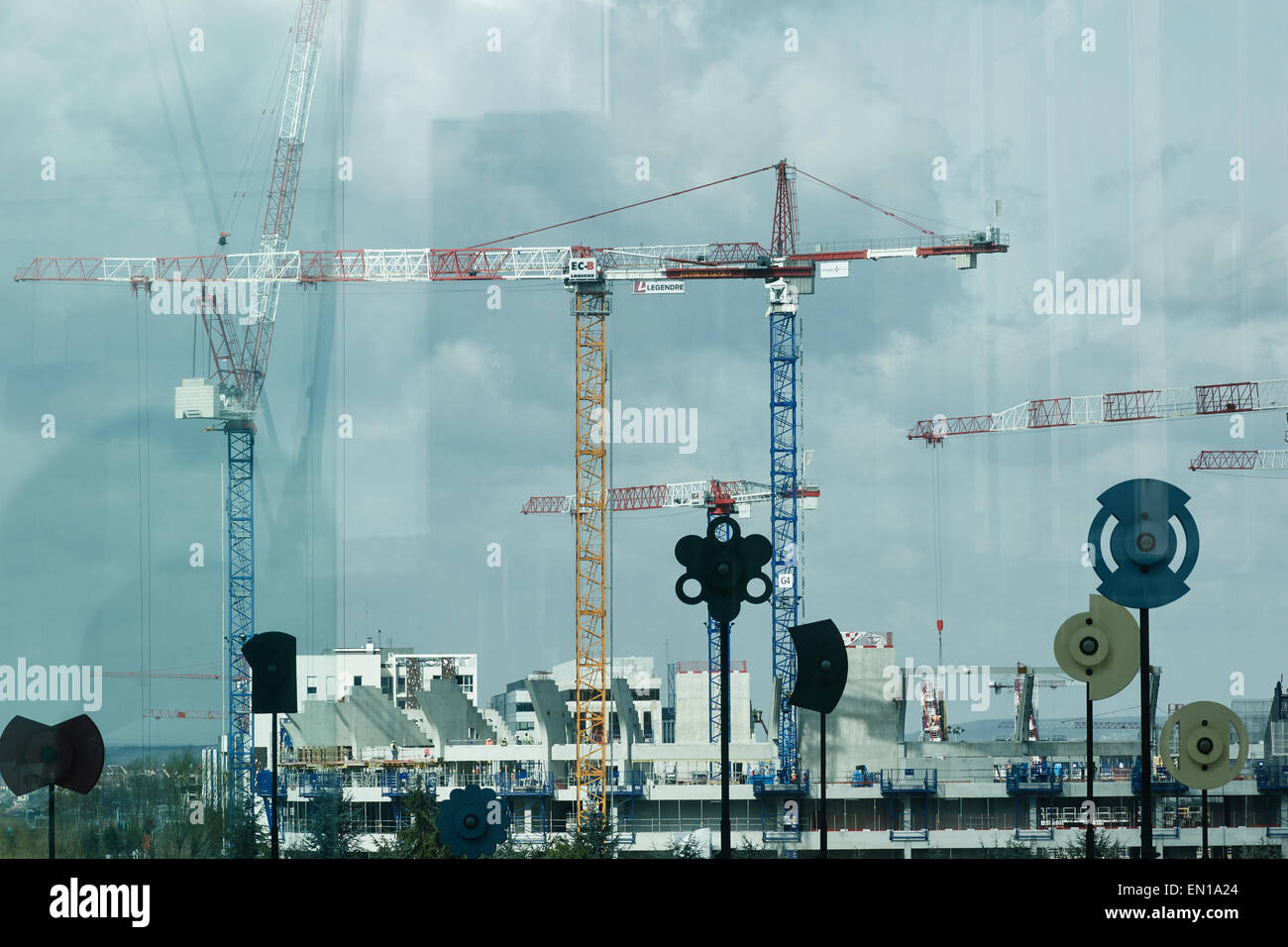Cranes on a building site and modern art seen through glass under the Grande Arche La Defense Paris France Europe Stock Photo