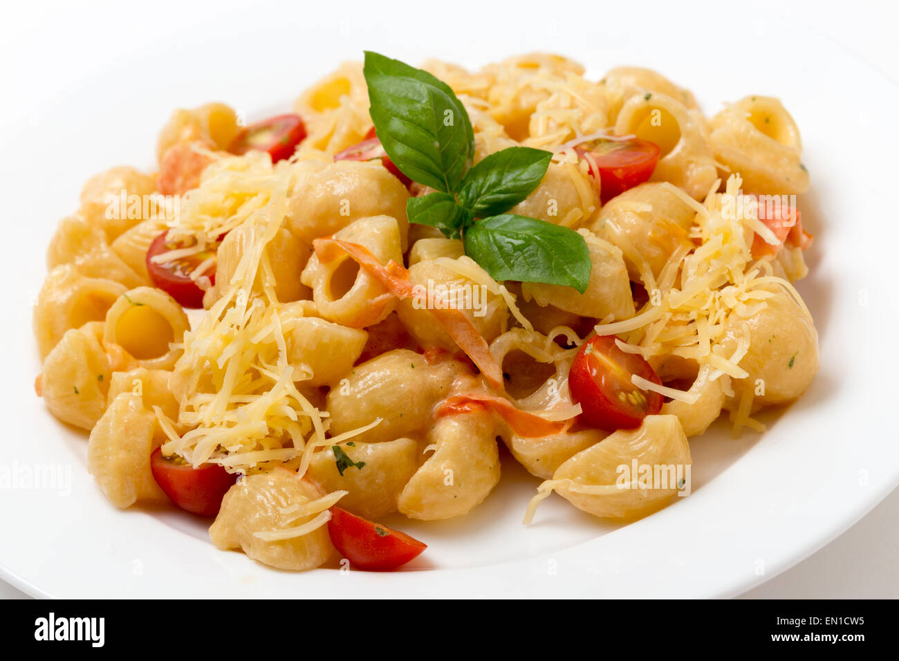 Gomiti rigata 'elbow' pasta tossed with tomatoes cooked in cream and with green pesto, cherry tomatoes and grated parmesan. Stock Photo