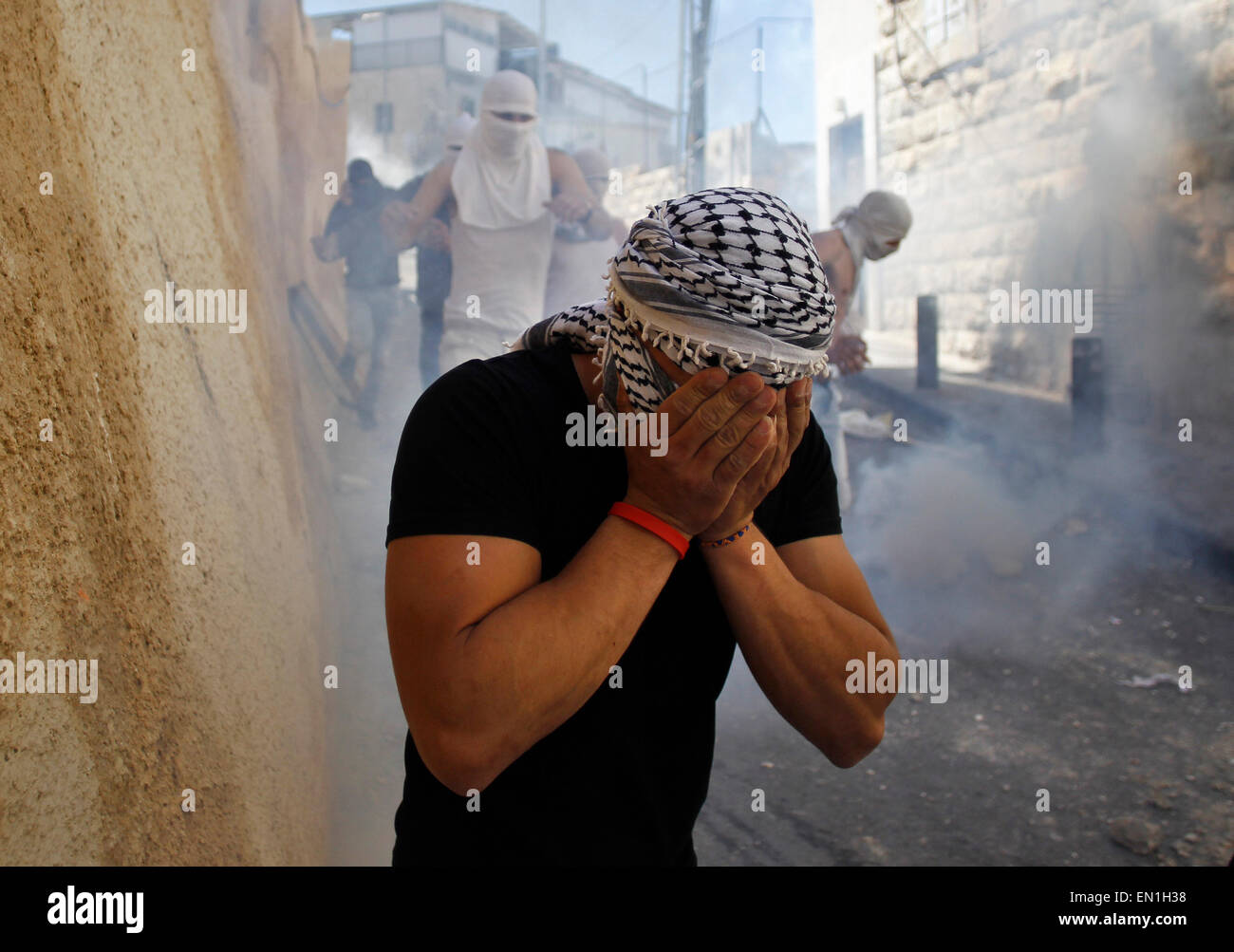(150425) -- JERUSALEM, April 25, 2015 (Xinhua) -- A masked Palestinian youth covers his face in the tear gas smoke during clashes between Palestinians and Israeli security forces in Al-Tur neighbourhood of East Jerusalem, on April 25, 2015. Israeli paramilitary Border Police said Saturday that it shot dead a knife-wielding Palestinian youth near an east Jerusalem checkpoint after he attempted to attack them. Ali Said Abu Ghanam, a 16-year-old resident of the Palestinian neighborhood of At-Tur, started running toward the policemen at the A-Zayyim checkpoint Friday overnight, according to a poli Stock Photo