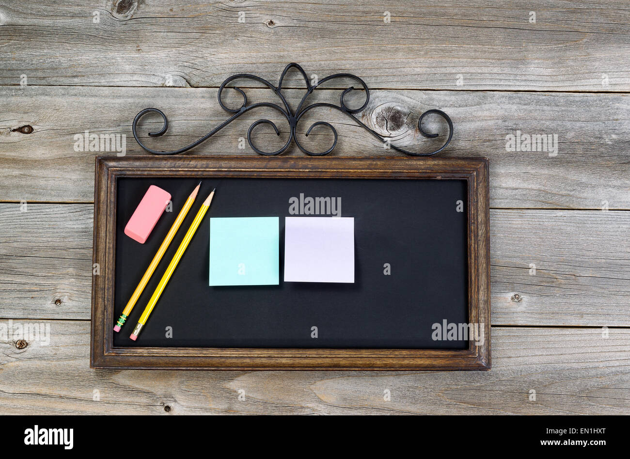 Old fashion chalkboard, pencils, eraser and paper notes on rustic wood