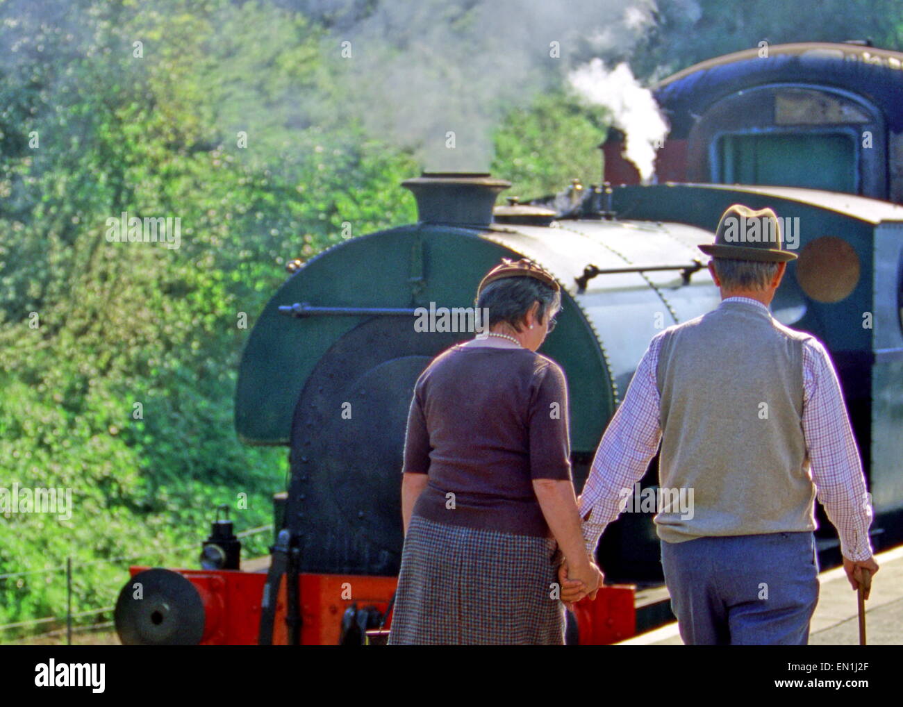 Man and woman catching steam train wearing 1940s, 1950s, 1930s clothes, with hats and cane Stock Photo