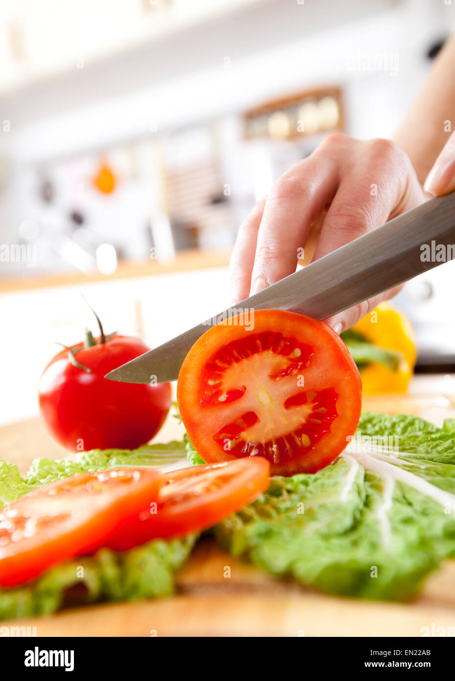 Woman's hands cutting fresh tomato on kitchen Stock Photo