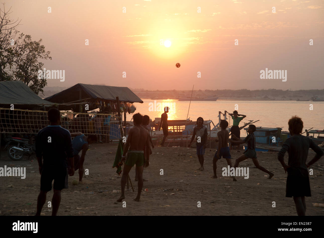 Burmese men play a ball game on the banks of the Ayarwaddy river as the sun sets in Mandalay  Myanmar Stock Photo