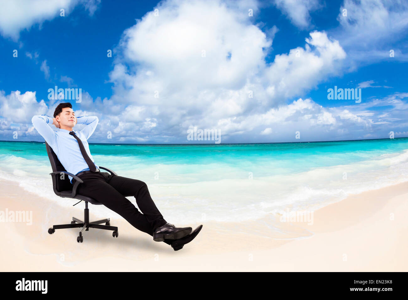 relaxed Young businessman sitting in a chair with beach background Stock Photo
