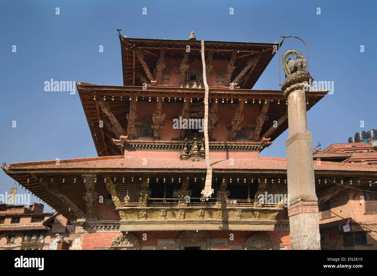 NEPAL, Kathmandu, Patan, Durbar Square, Bhimsen Hindu Temple (rebuilt 1682) with Lion Statue on a  column in foreground Stock Photo