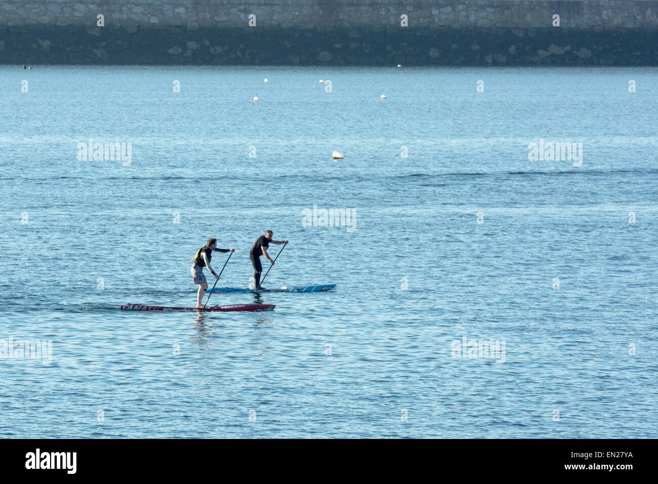 Two people paddleboarding on sunny evening Stock Photo