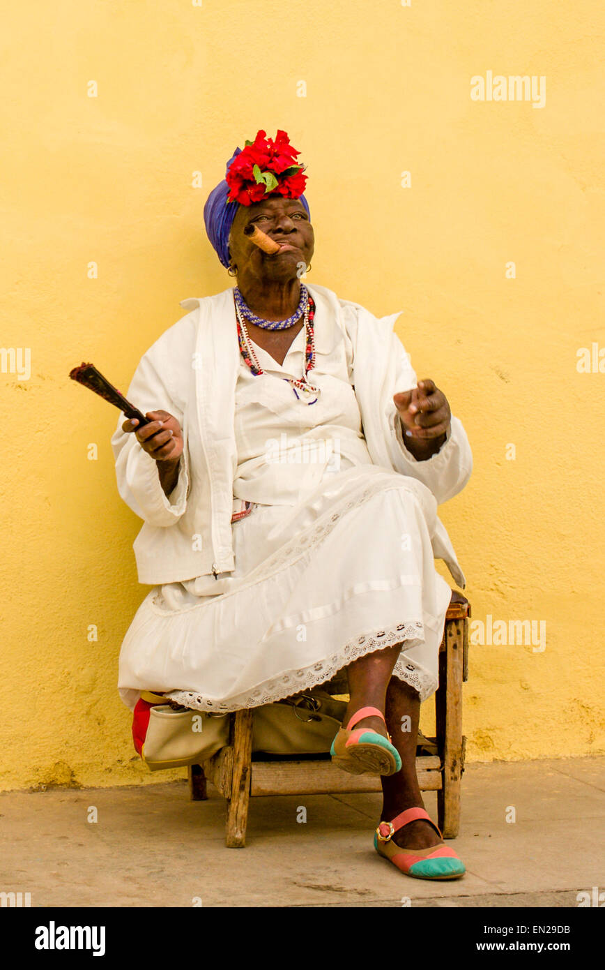 Elderly Cuban woman smoking a huge cigar as she poses for tourists in old Havana, Cuba. Stock Photo