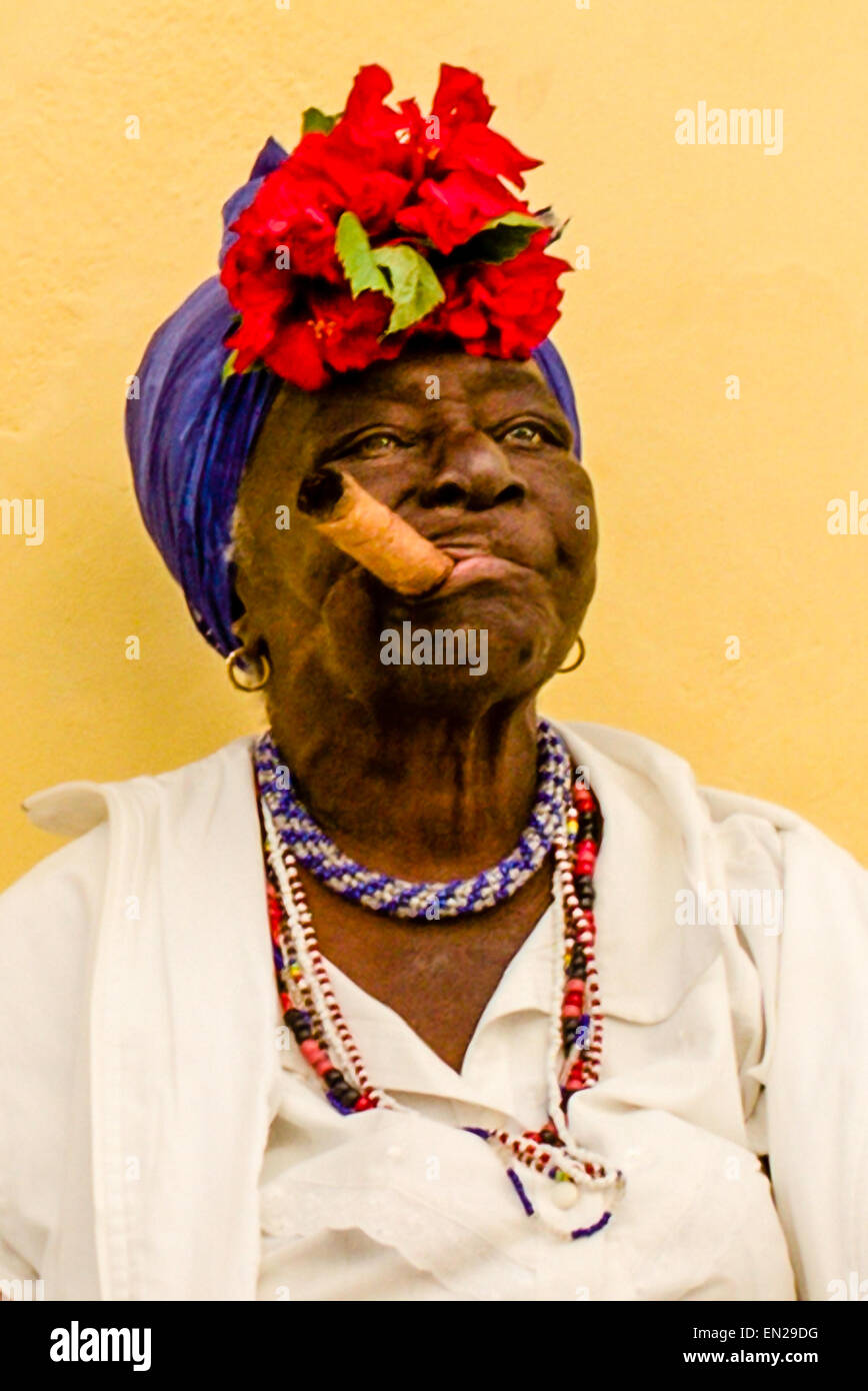 Elderly Cuban woman smoking a huge cigar as she poses for tourists in old Havana, Cuba. Stock Photo