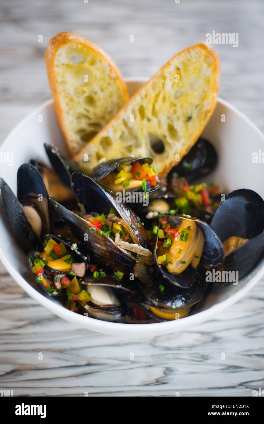 Mussels with herbs and chopped pepper with toasted bread. Stock Photo