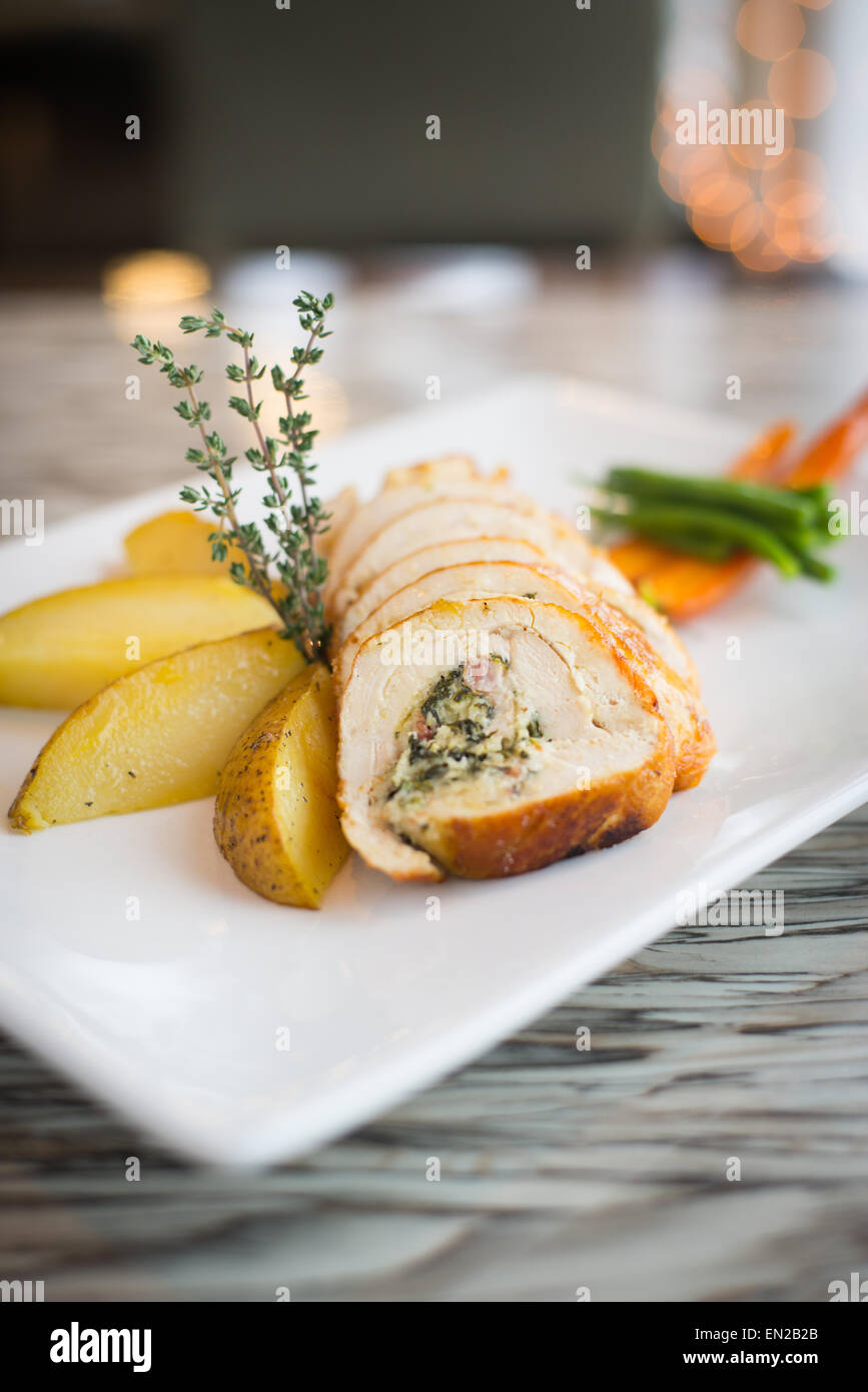 Vertical view of chicken roulade with potato wedges, herbs, and vegetables Stock Photo