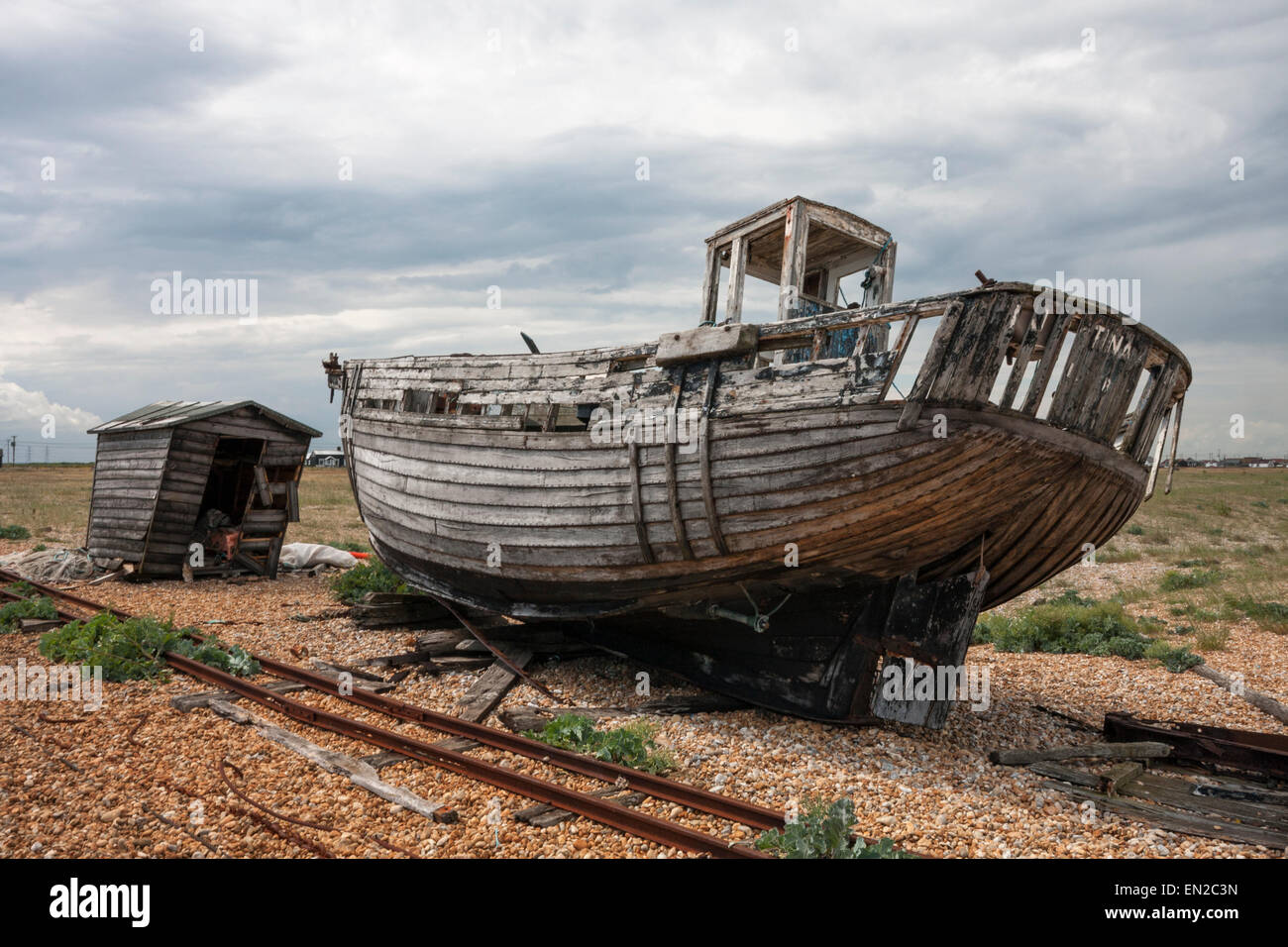 Abandoned wreck of fishing boat 'Tina' and dilapidated old fishing hut Dungeness Kent England UK Stock Photo