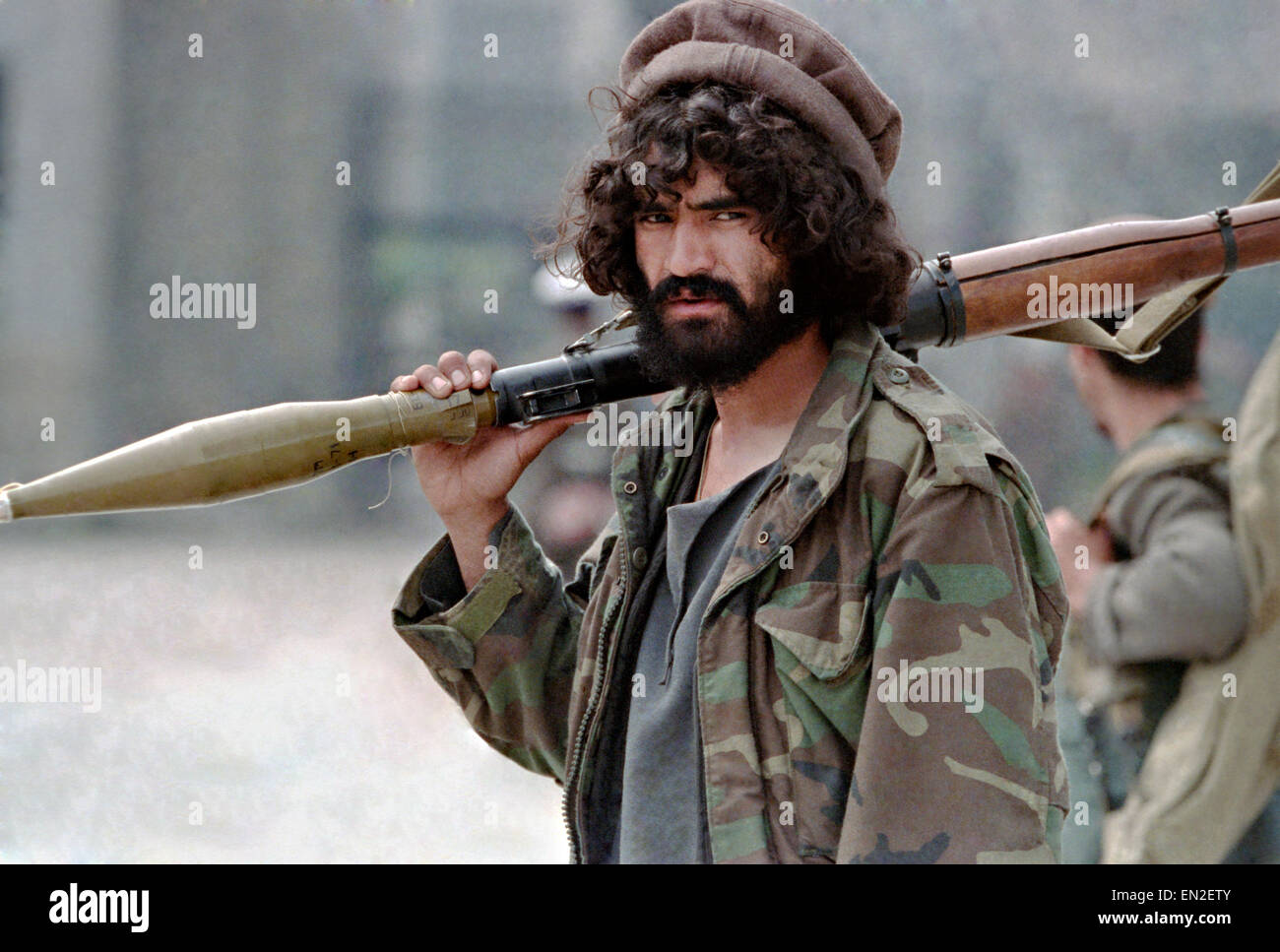 An Afghan mujahideen fighter with Jamayat-E-Islami carries a shoulder fired Rocket-propelled grenade during fighting against Hezb-i Islami forces following the fall of the capital April 19, 1992 in Kabul, Afghanistan. Fighting between mujahideen factions began almost immediately after they captured the city. Stock Photo
