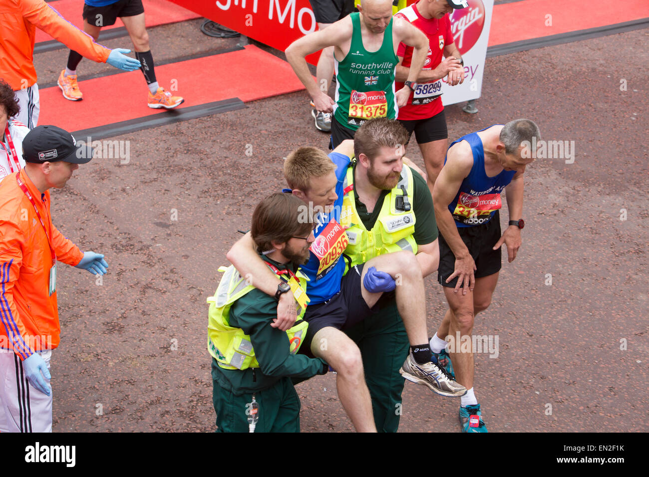 A runner is carried after collapsing at the finish line of the Virgin