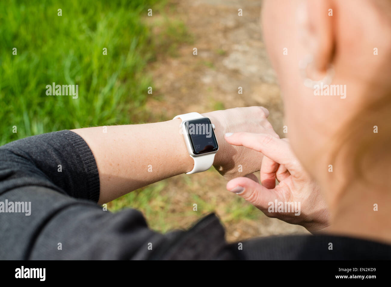 Ostfildern, Germany - April 26, 2015: A middle aged Caucasian woman is checking her Apple Watch displaying the home screen with Stock Photo