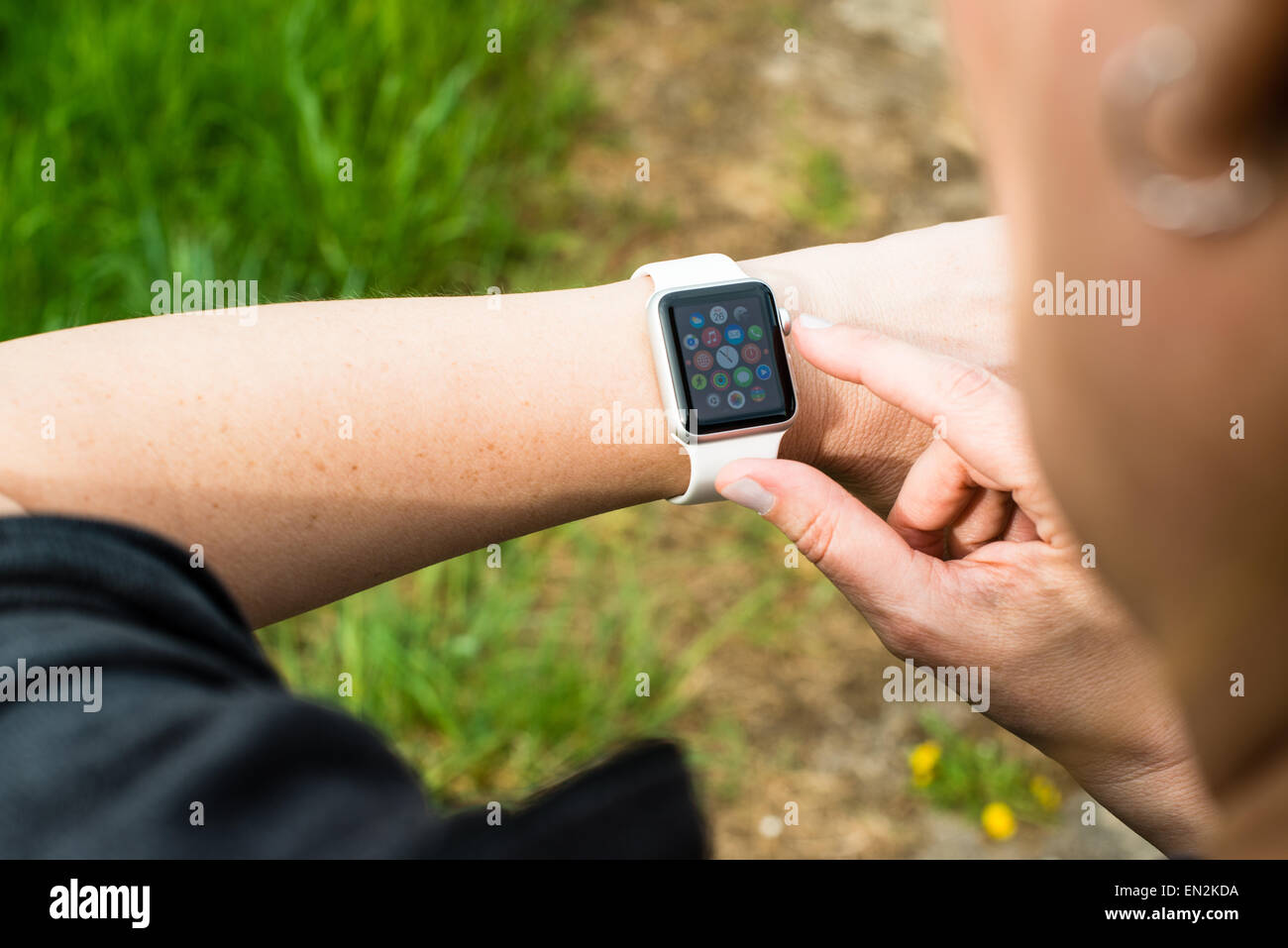 Ostfildern, Germany - April 26, 2015: A middle aged Caucasian woman is checking her Apple Watch displaying the main screen with Stock Photo