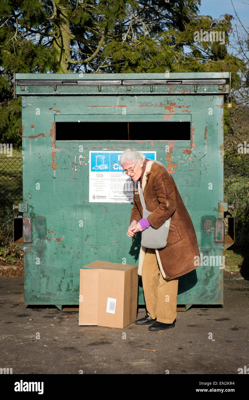 Elderly lady recycling paper and cardboard at a recycling centre. Stock Photo