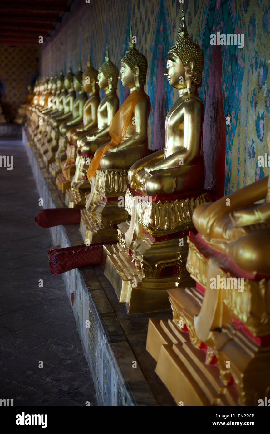 Row of golden seated buddhas in front of decorative wall in a Buddhist ...