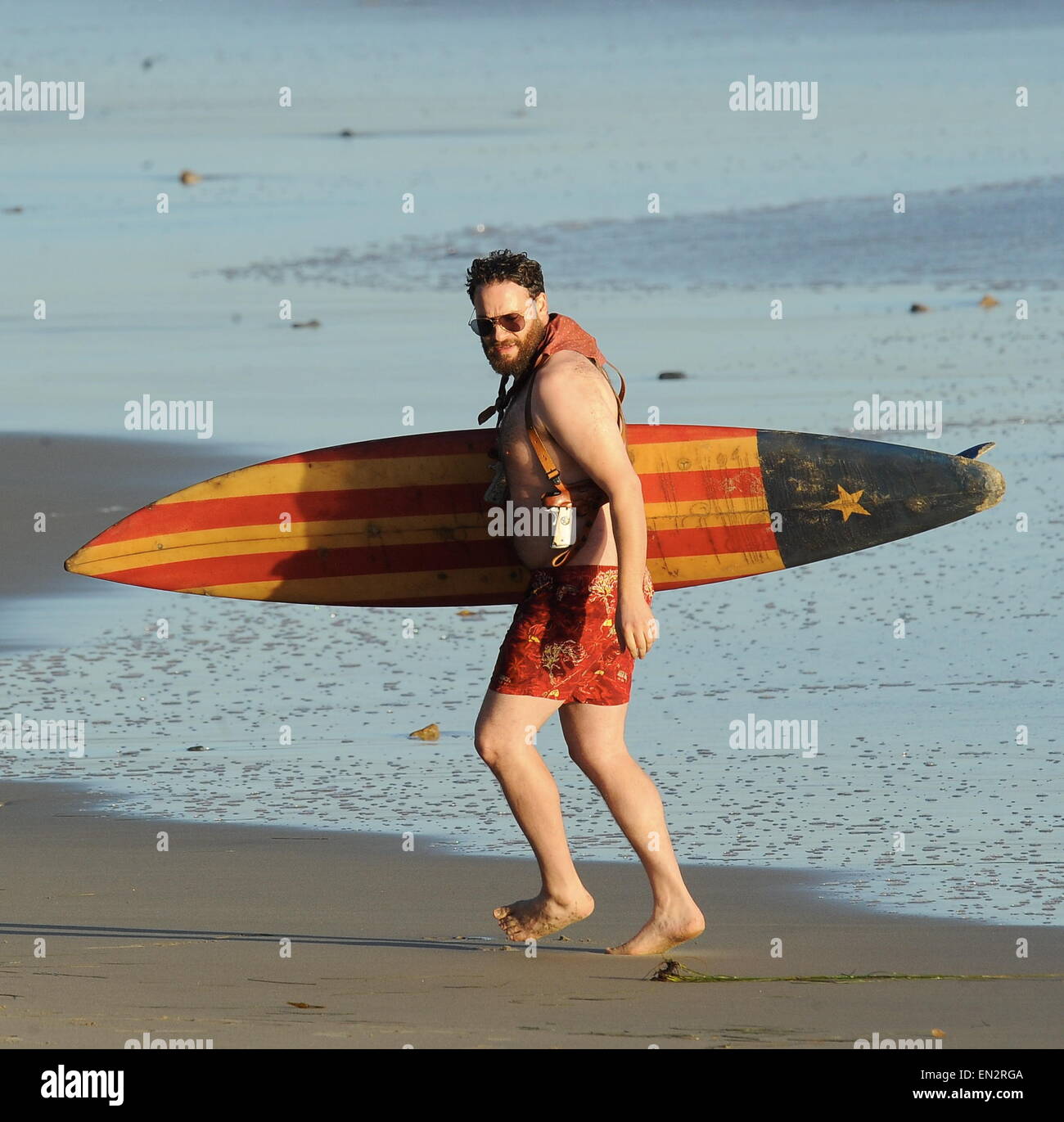 Actor Seth Rogen is lock and loaded on the beach and ready to surf for the new movie "Zeroville" filming in Malibu Ca. The comedian was seen holding a surf board and 2 guns in their holsters with swimming trunks while filming a sunset scene on the beach. The new movie is also produced and directed by his good pal James Franco.  Featuring: Seth Rogen Where: Malibu, California, United States When: 22 Oct 2014 Stock Photo