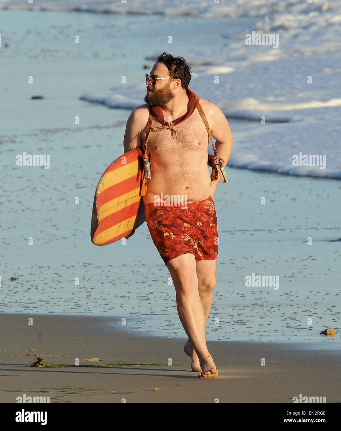 Actor Seth Rogen is lock and loaded on the beach and ready to surf for the new movie 'Zeroville' filming in Malibu Ca. The comedian was seen holding a surf board and 2 guns in their holsters with swimming trunks while filming a sunset scene on the beach. The new movie is also produced and directed by his good pal James Franco.  Featuring: Seth Rogen Where: Malibu, California, United States When: 22 Oct 2014 Stock Photo