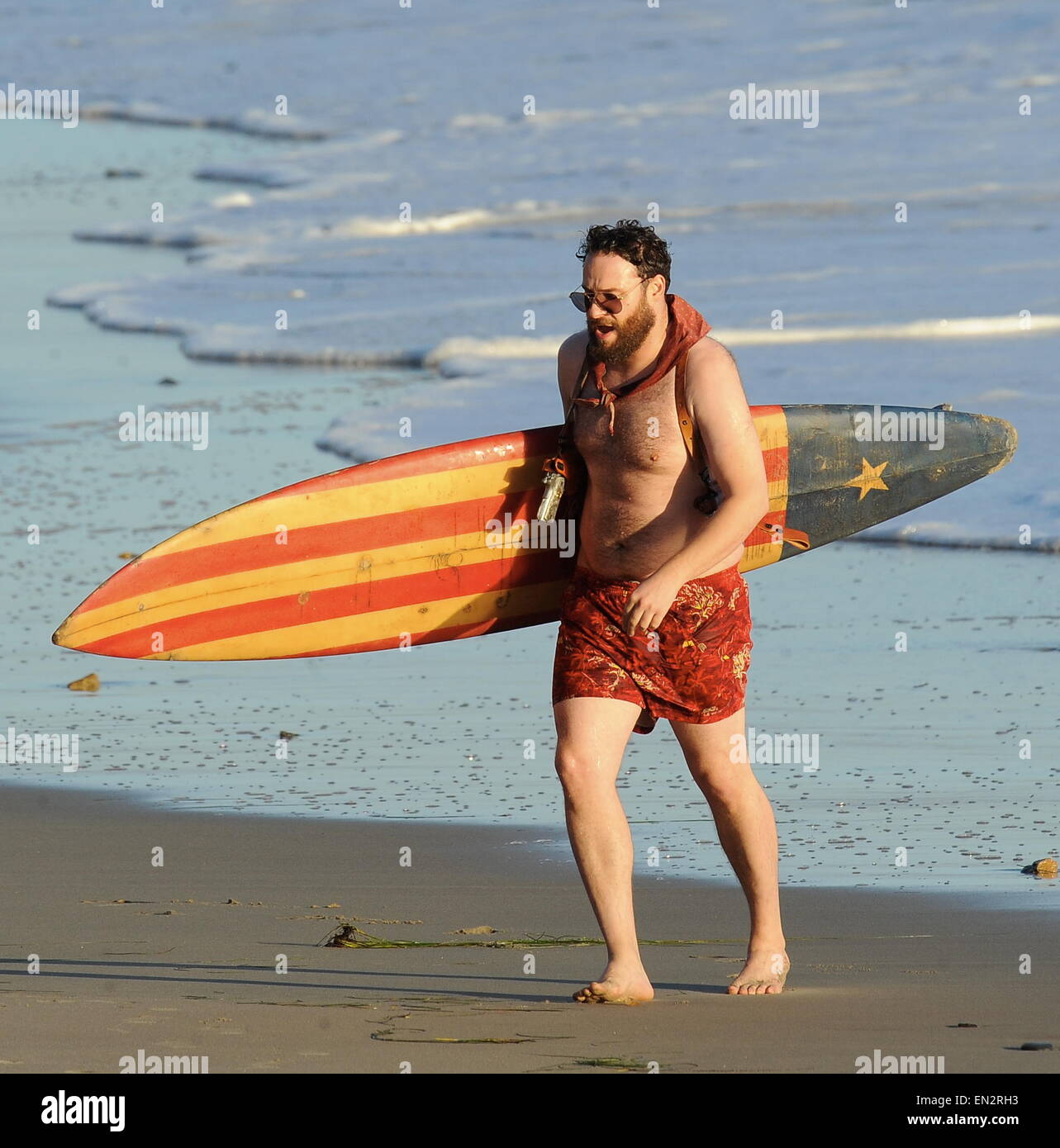 Actor Seth Rogen is lock and loaded on the beach and ready to surf for the new movie 'Zeroville' filming in Malibu Ca. The comedian was seen holding a surf board and 2 guns in their holsters with swimming trunks while filming a sunset scene on the beach. The new movie is also produced and directed by his good pal James Franco.  Featuring: Seth Rogen Where: Malibu, California, United States When: 22 Oct 2014 Stock Photo