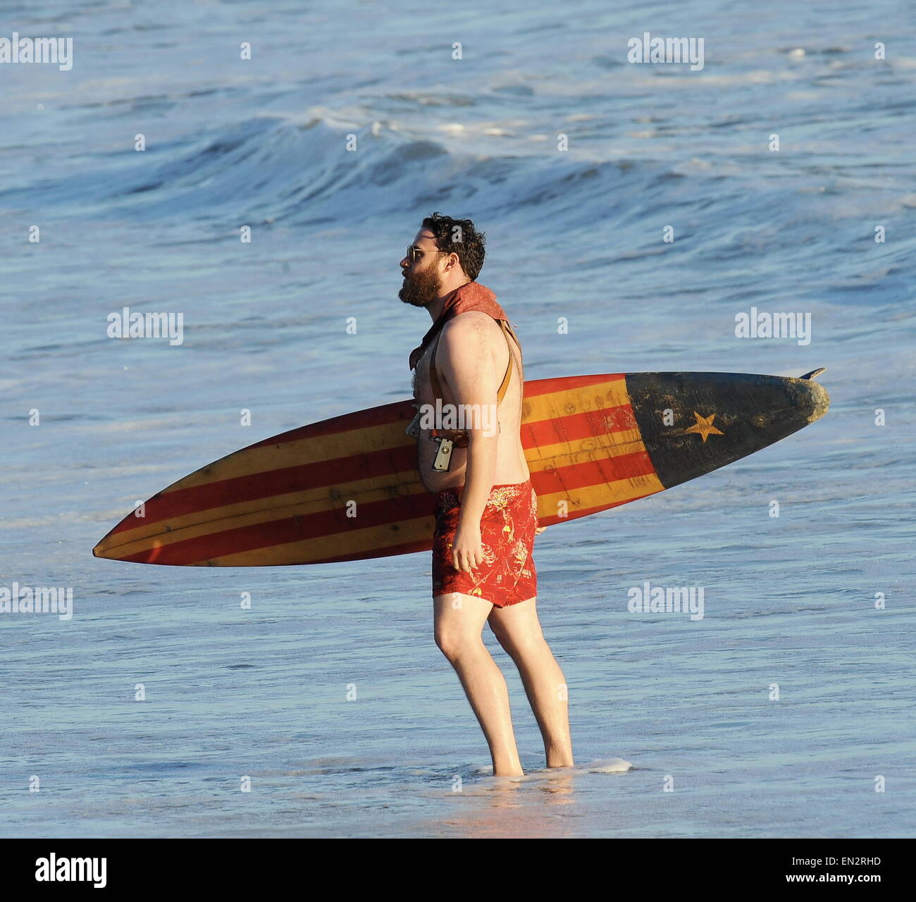 Actor Seth Rogen is lock and loaded on the beach and ready to surf for the new movie "Zeroville" filming in Malibu Ca. The comedian was seen holding a surf board and 2 guns in their holsters with swimming trunks while filming a sunset scene on the beach. The new movie is also produced and directed by his good pal James Franco. Featuring: Seth Rogen Where: Malibu, California, United States When: 22 Oct 2014 Stock Photo