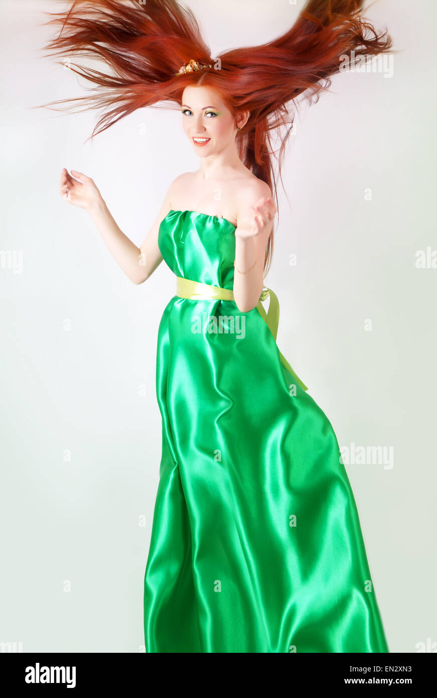 Red-haired girl in a green dress with flowing hair Stock Photo