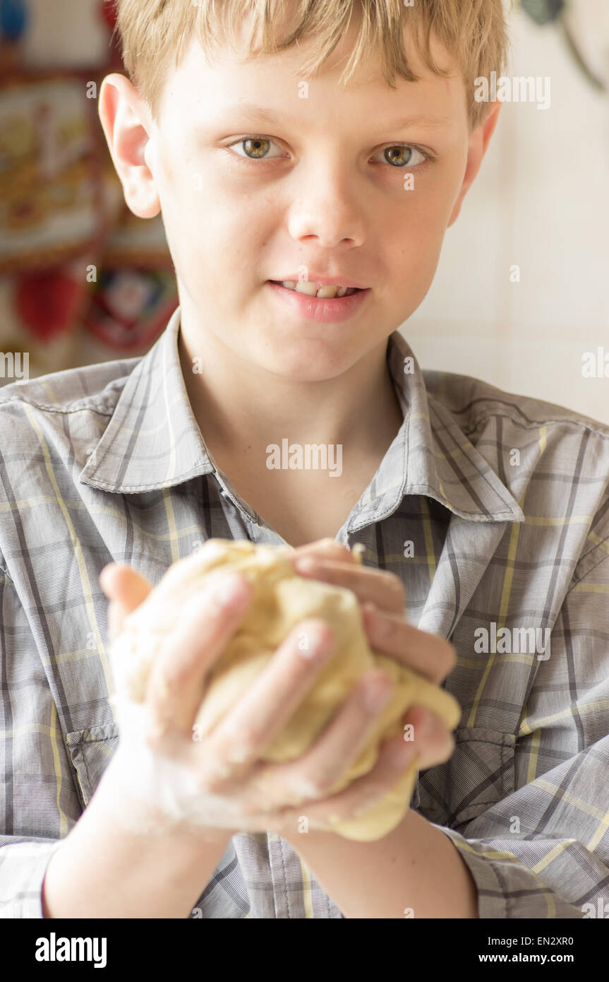 Smiling boy holds in hands kneaded dough Stock Photo