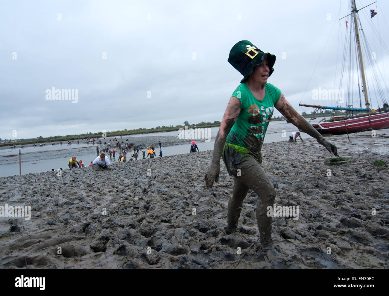Wearing a Irish top hat a brave lady completes the 2015 maldon mud race. Stock Photo