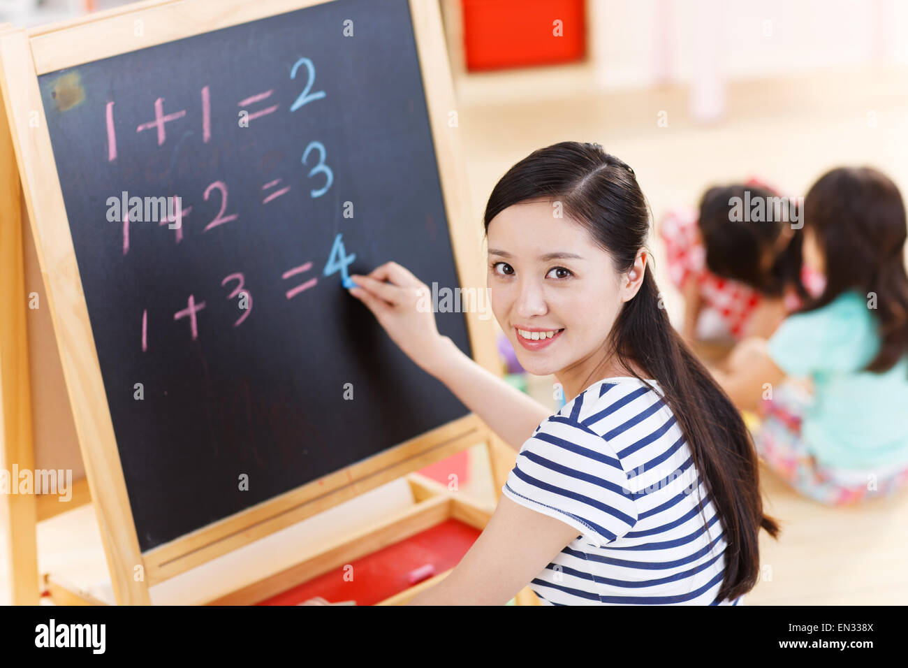 A kindergarten teacher was writing on the blackboard Stock Photo
