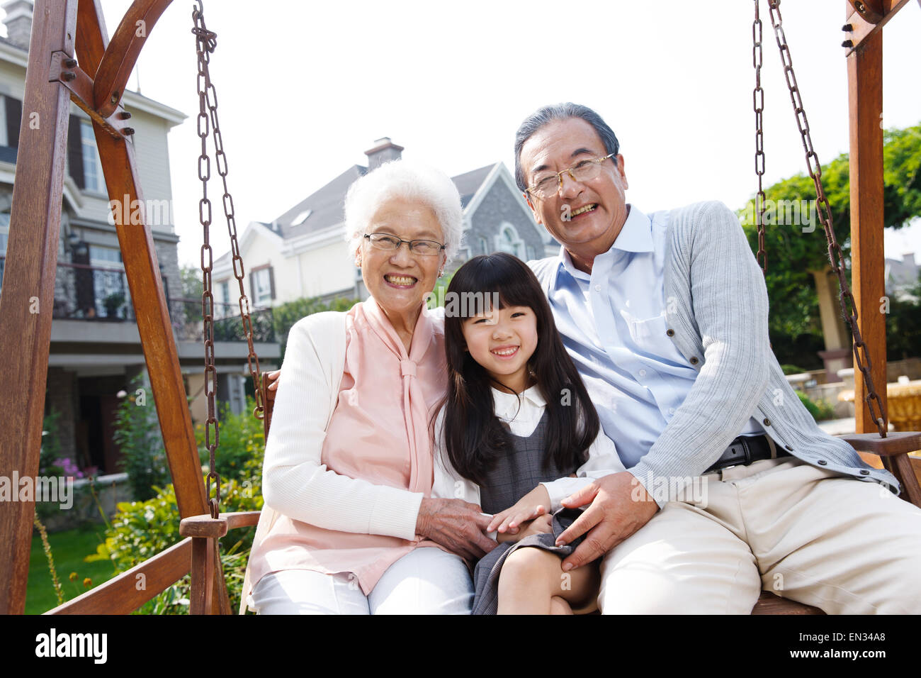 Grandparents and grandchild sit outside in the rocking chair Stock Photo