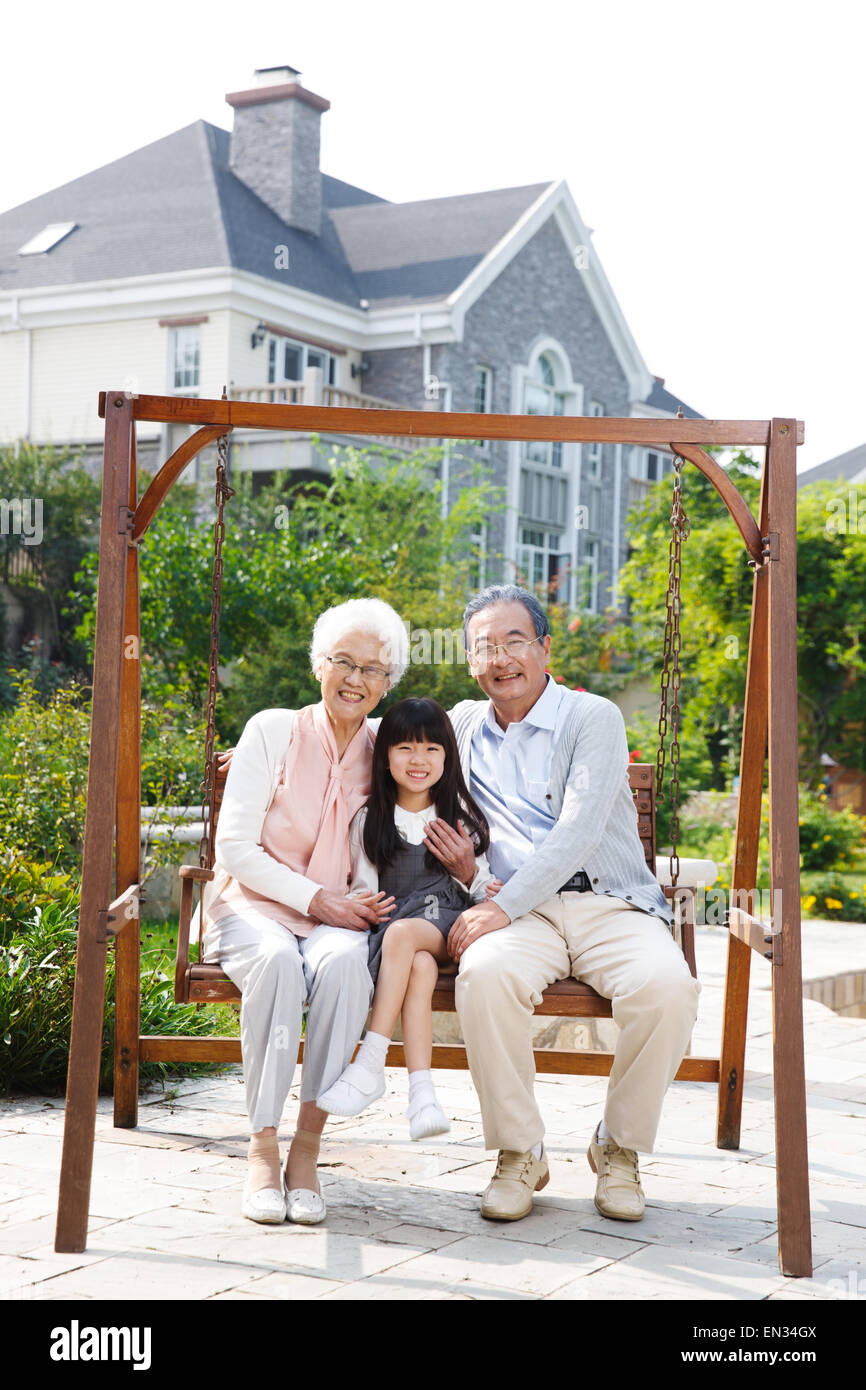 Grandma and grandpa with a small granddaughter swing Stock Photo