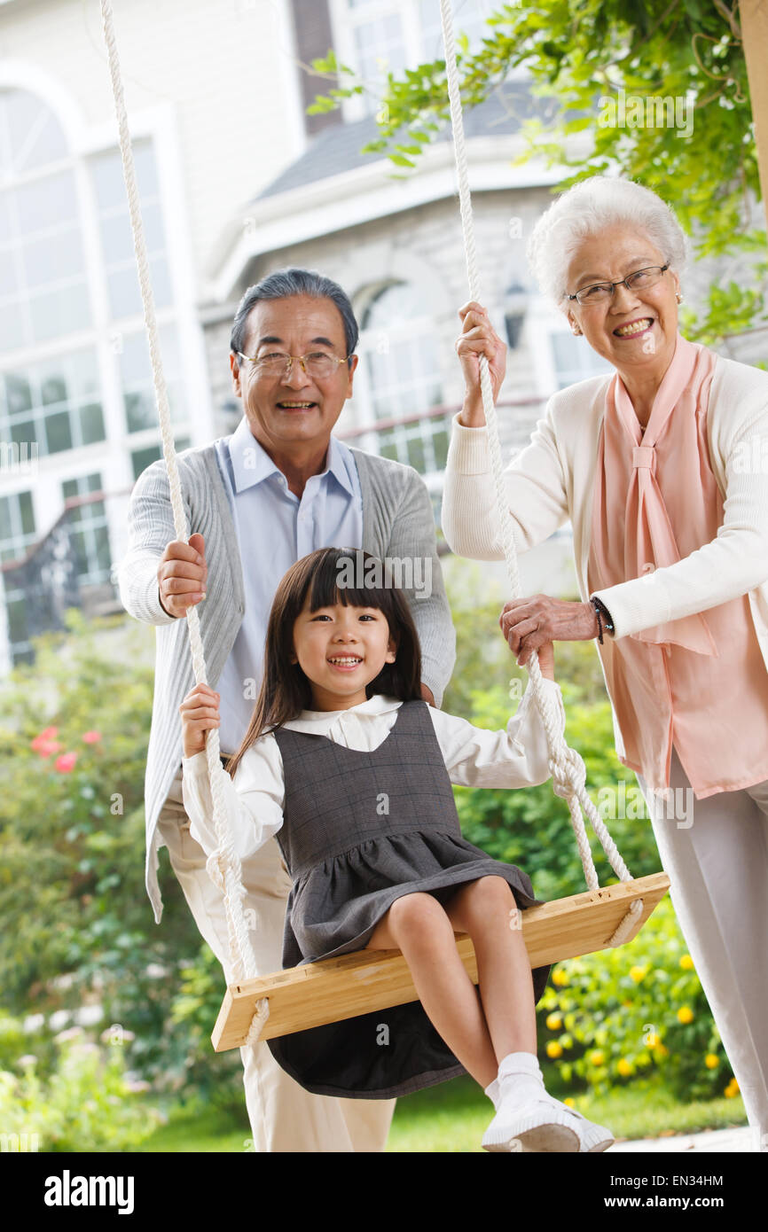 Grandma and grandpa with a small granddaughter swing Stock Photo