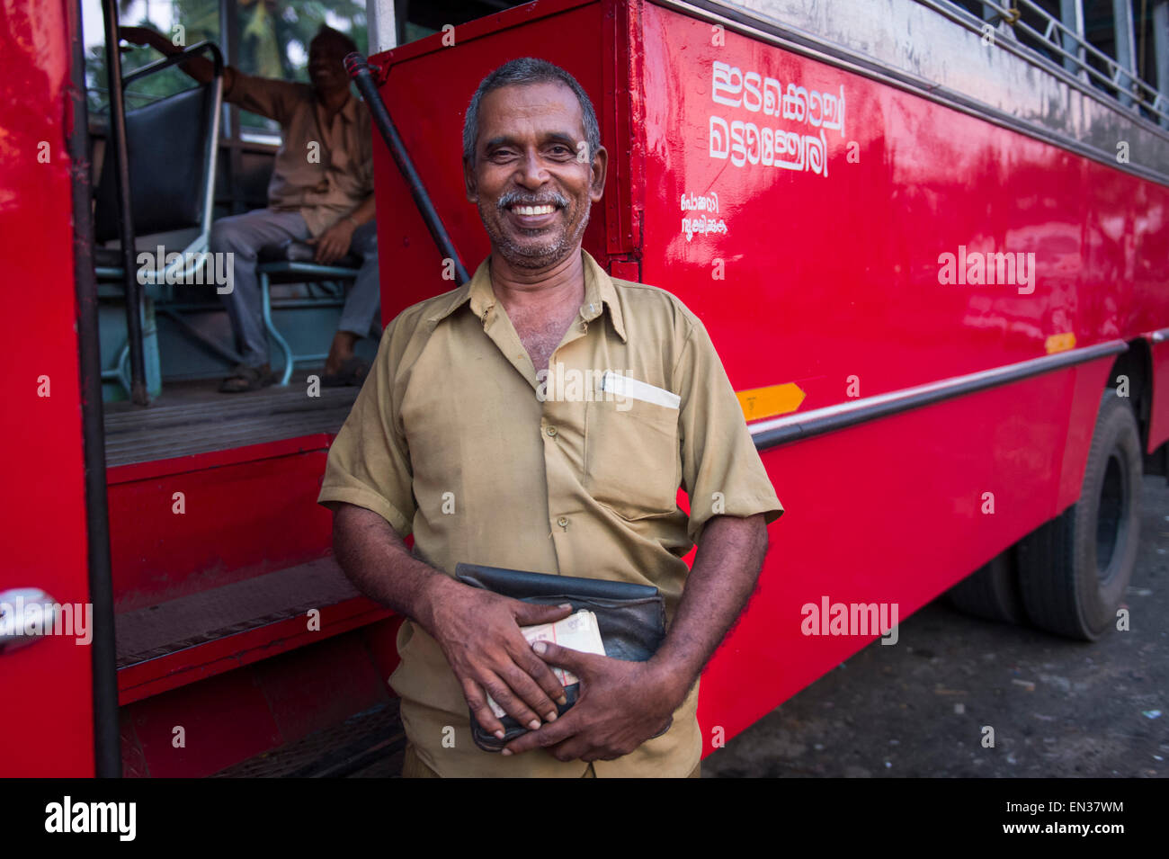Bus driver in front of a red bus, Kerala, India Stock Photo