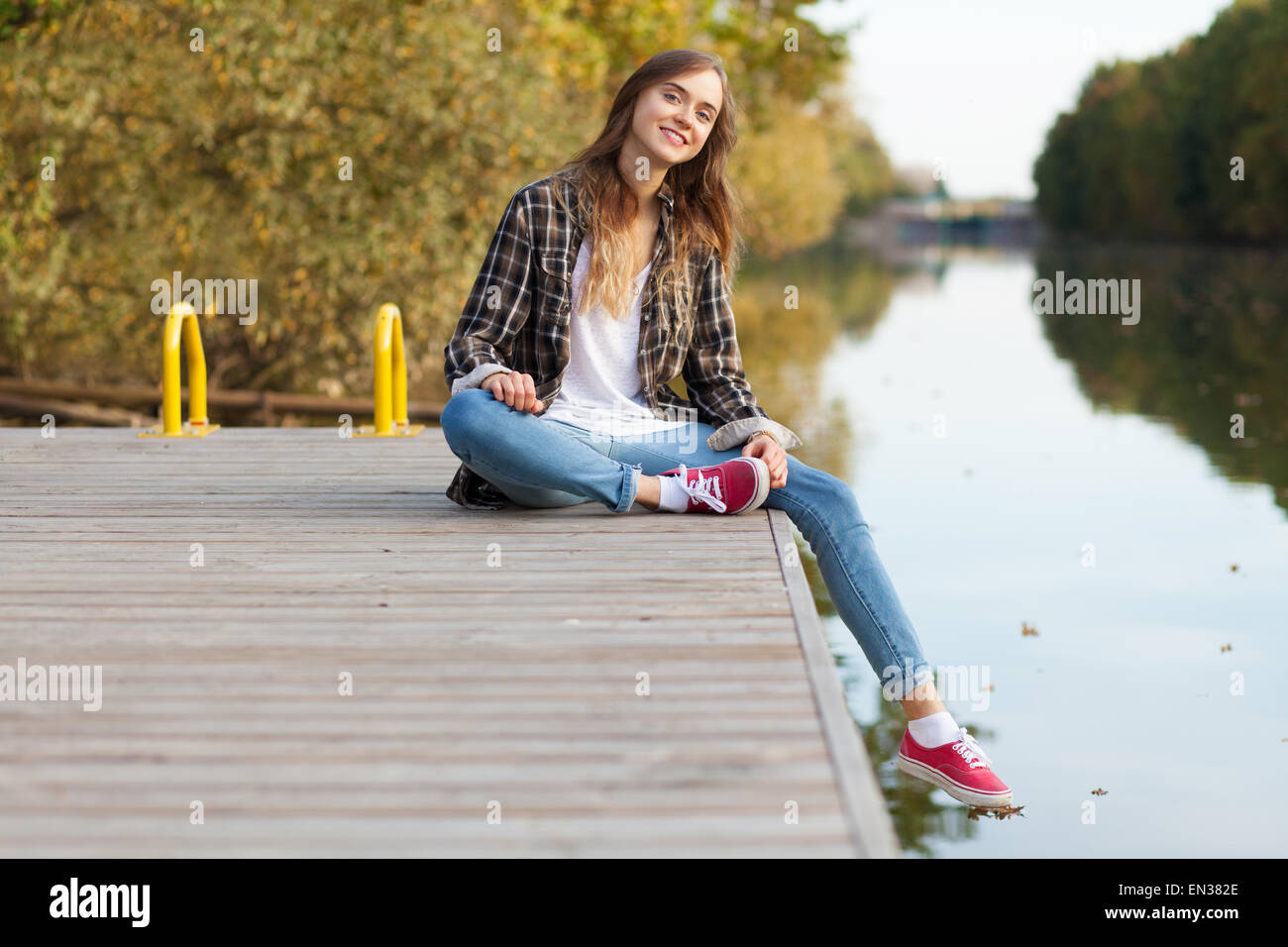 Young beautiful girl sitting on a pier Stock Photo