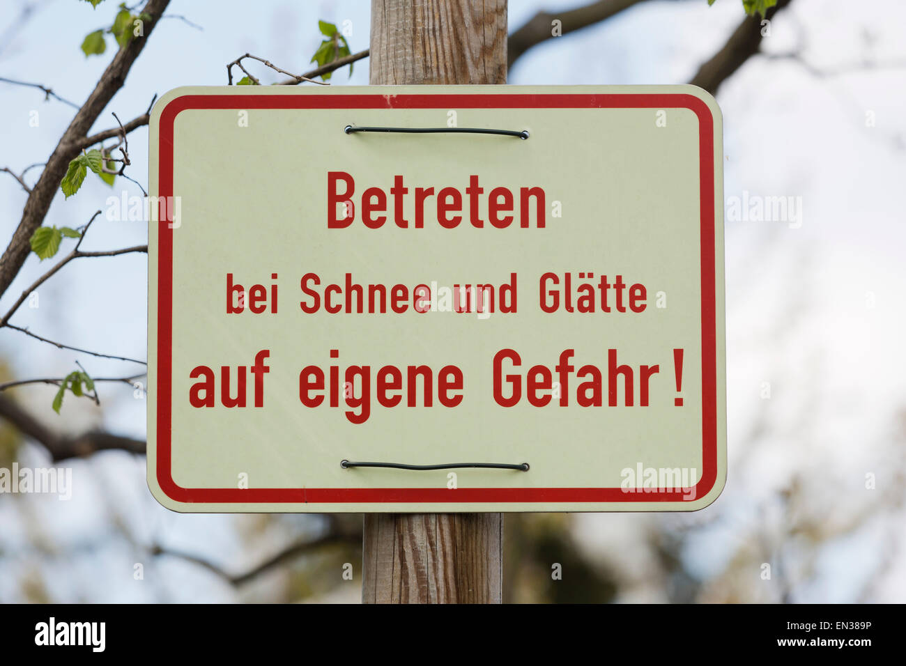 Sign in German, saying 'entering in snowy and icy conditions at your own risk' Stock Photo