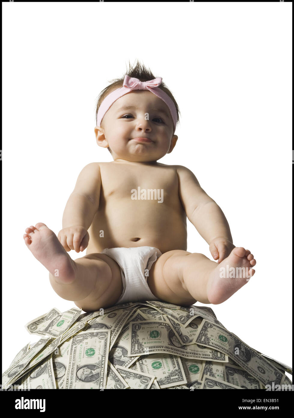 Baby girl sitting on pile of US currency Stock Photo
