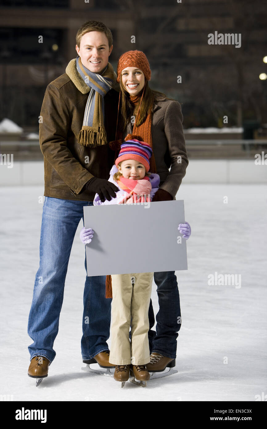 Man and woman with girl holding blank sign outdoors in winter Stock Photo