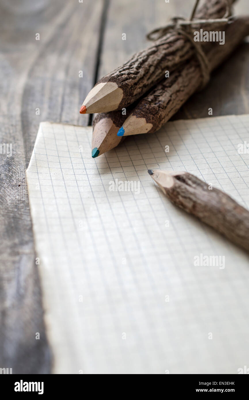 Group of bark covered branch multicolored pencils on wooden  background Stock Photo