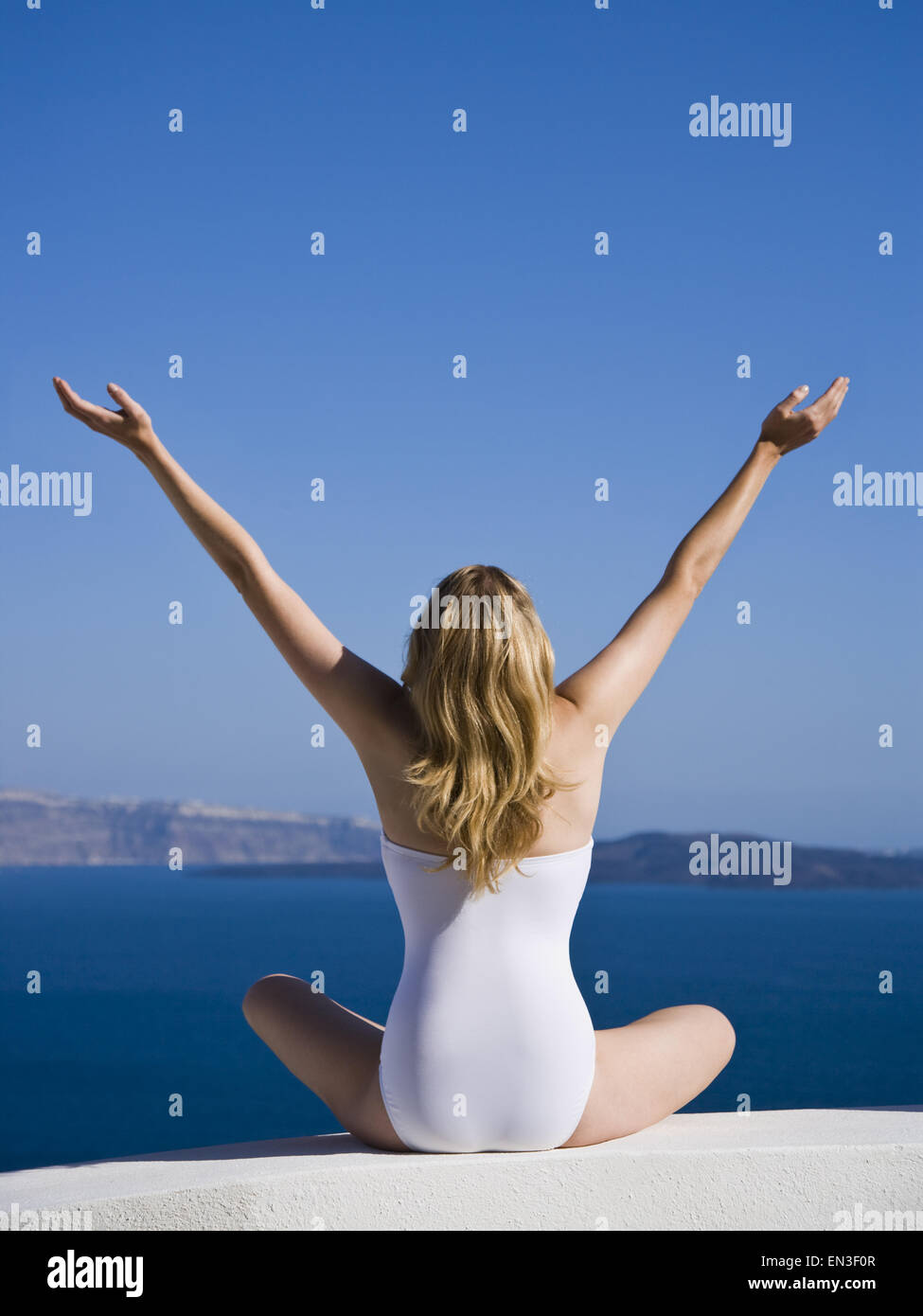 Rear view of woman in swimsuit with arms up Stock Photo