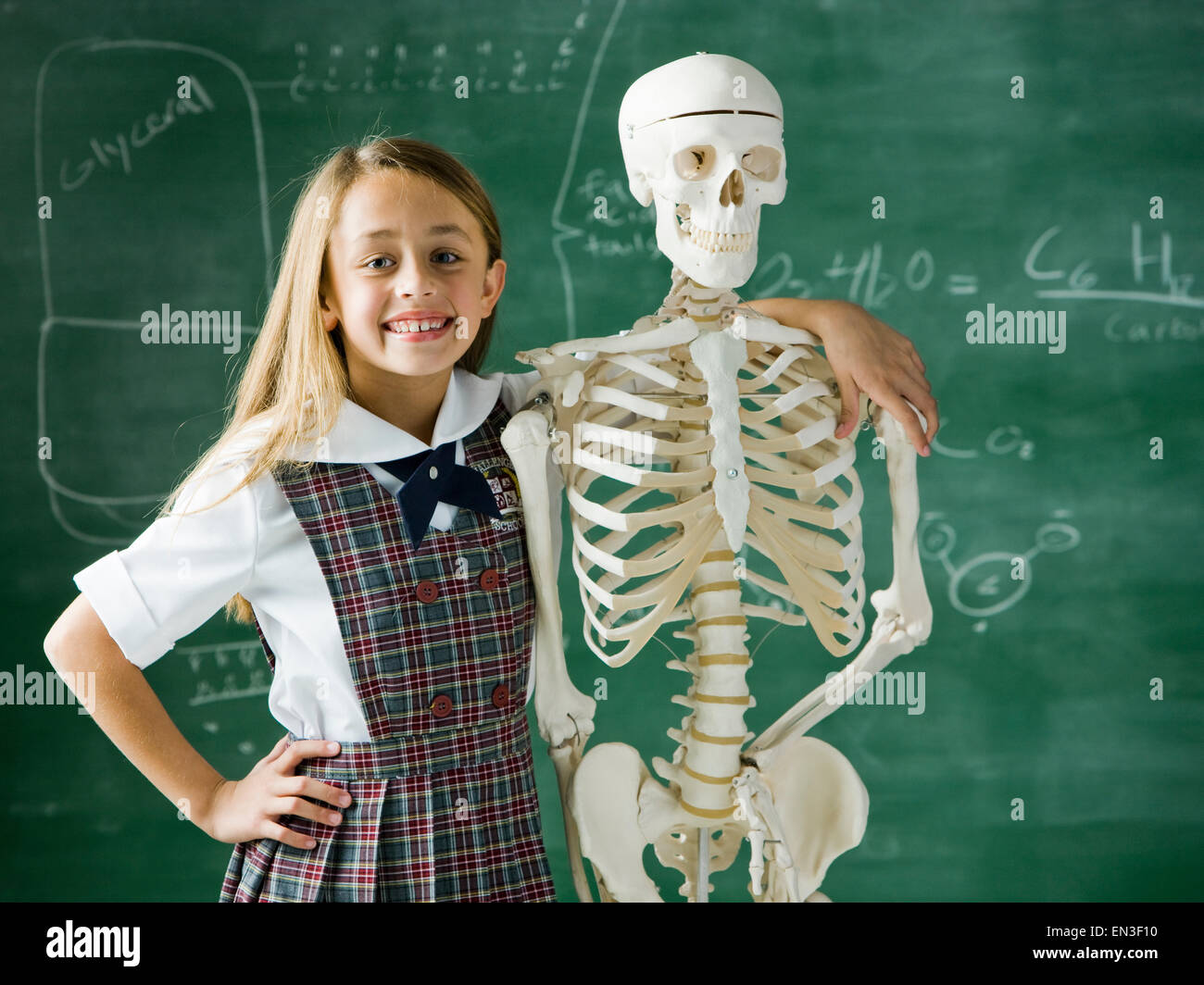 girl in a classroom standing in front of a chalkboard with a human skeleton Stock Photo