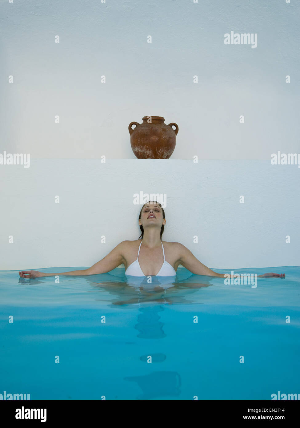Woman in pool leaning on wall under urn Stock Photo