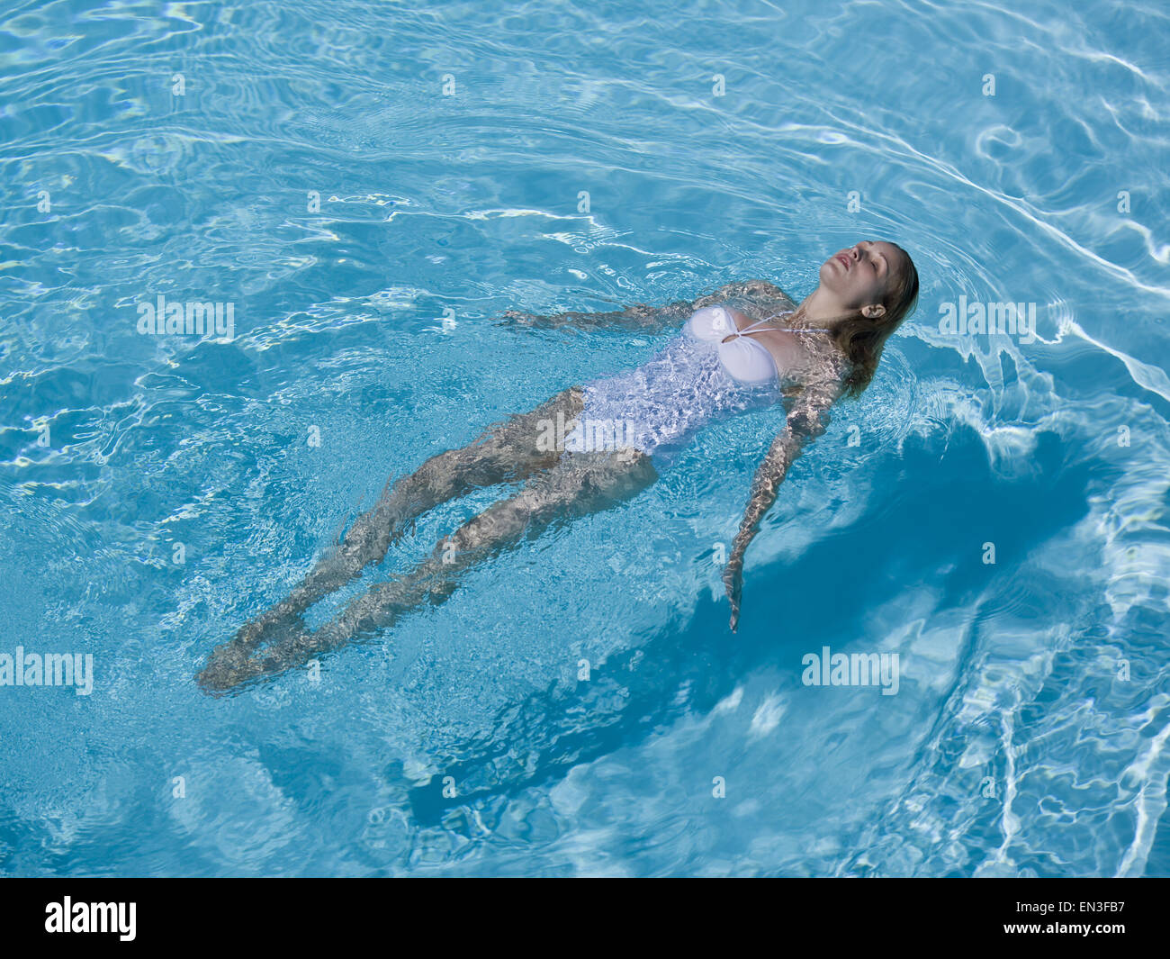 Woman floating in pool Stock Photo