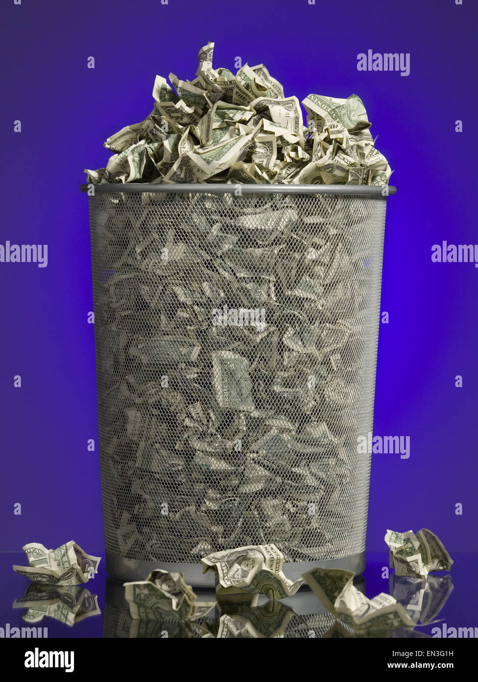 Crumpled money in waste paper basket Stock Photo