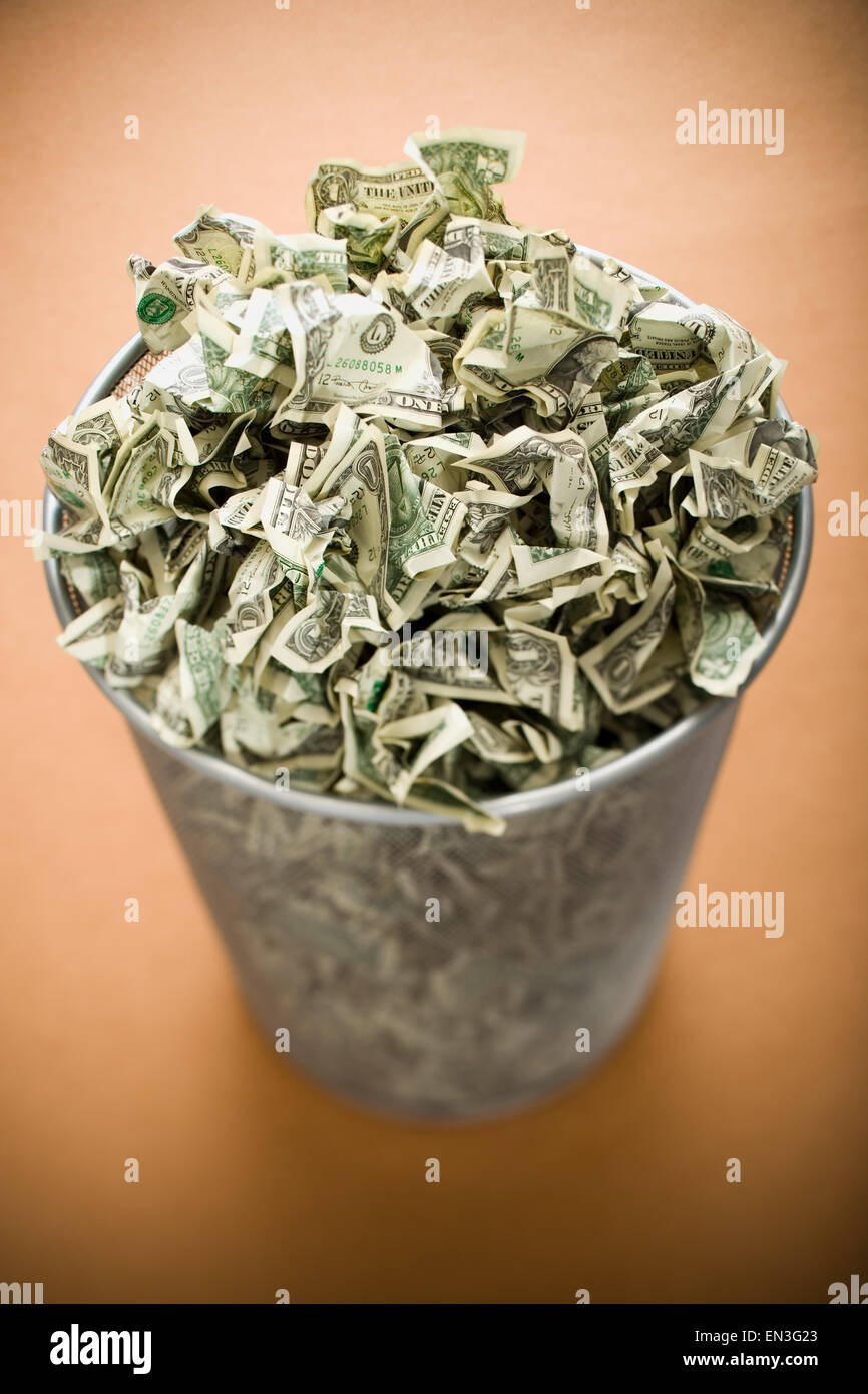 Waste paper basket with crumpled money Stock Photo