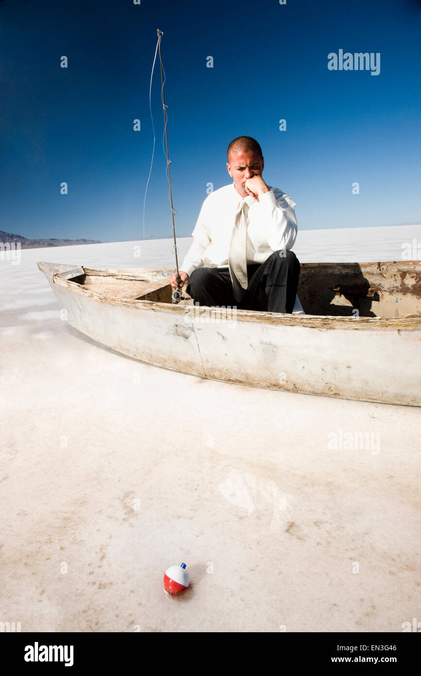 businessman fishing from a boat in the middle of the desert Stock Photo