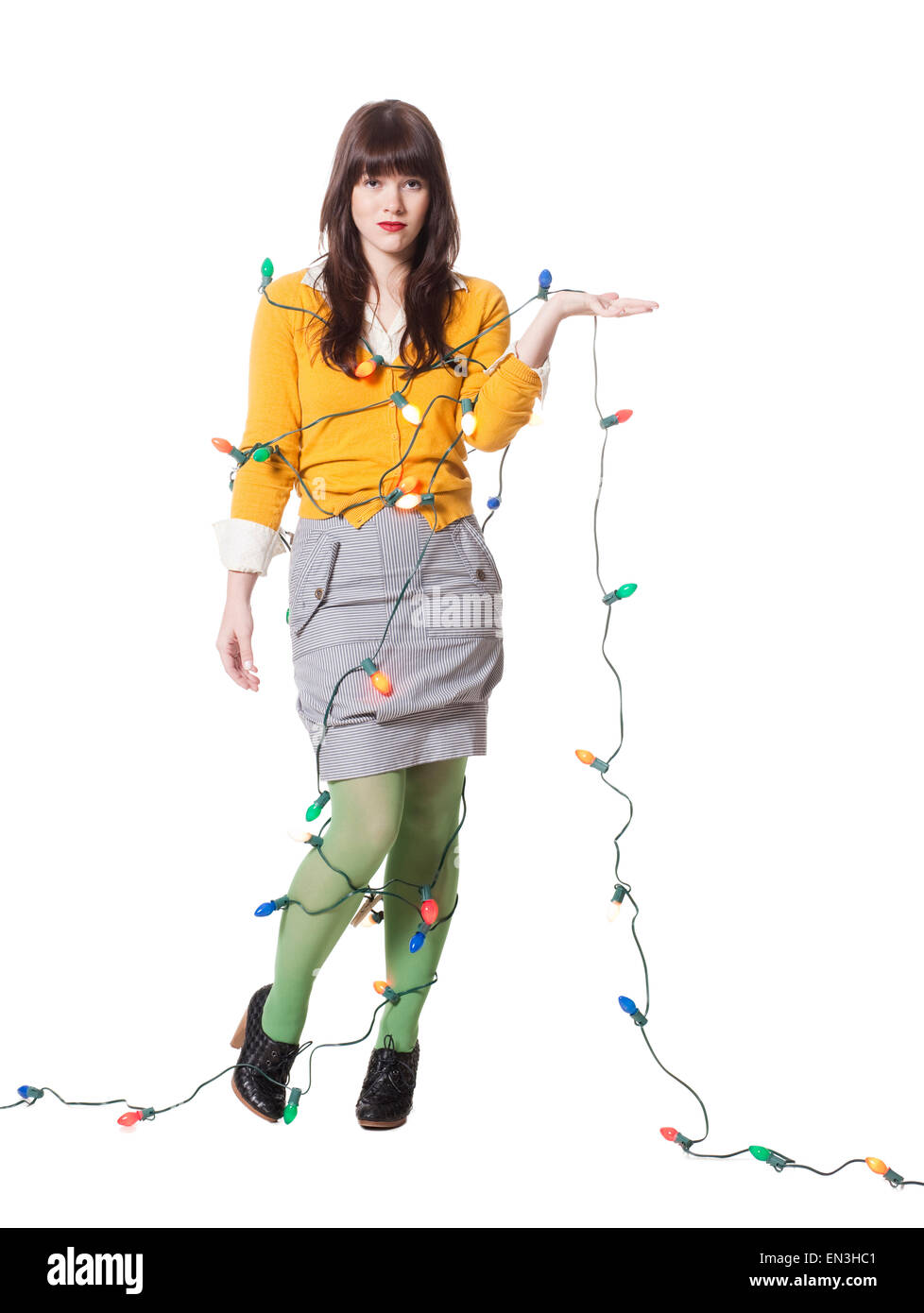 Studio shot of young woman wrapped in illuminated Christmas lights Stock Photo
