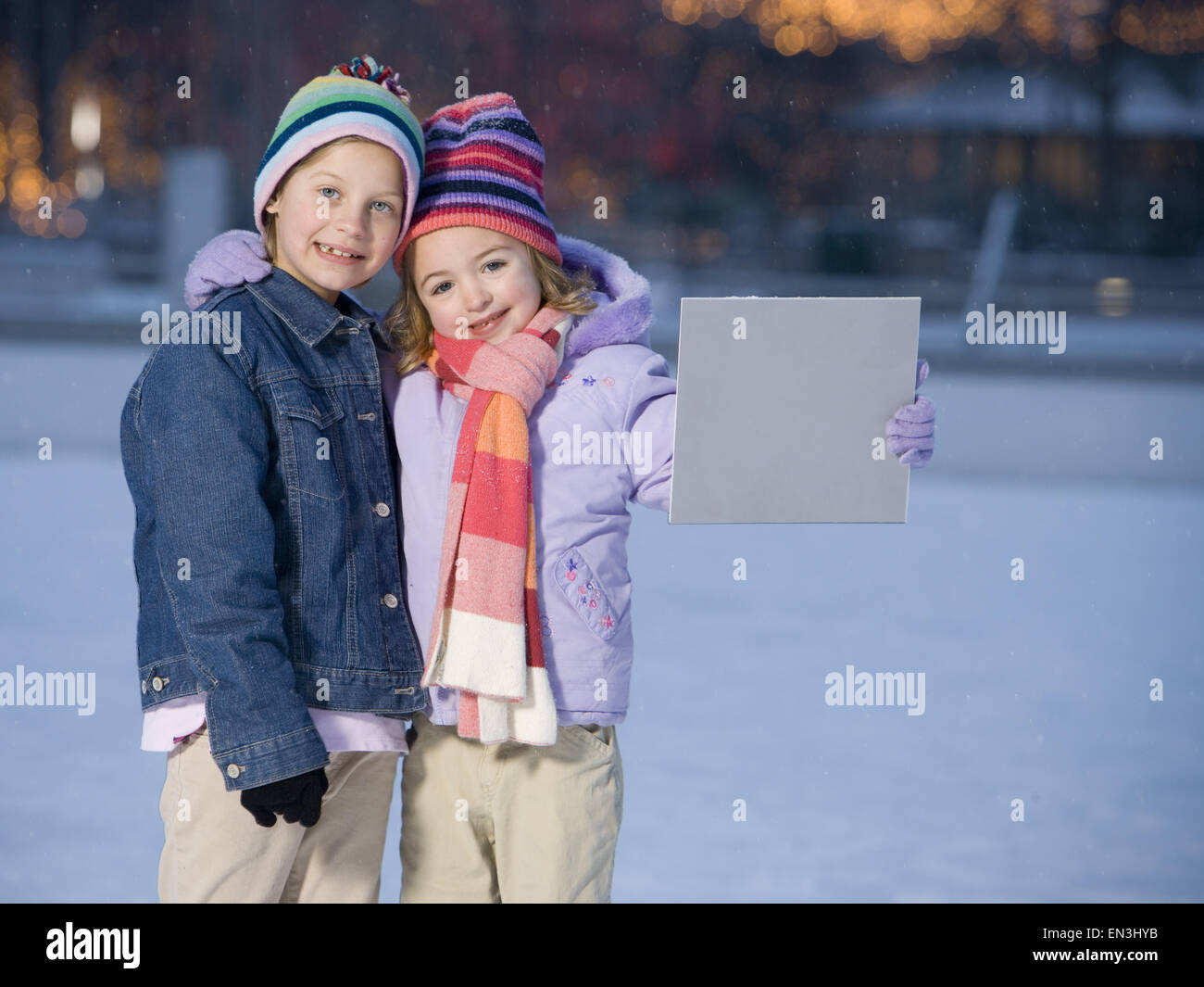 Two girls outdoors in winter with blank sign Stock Photo